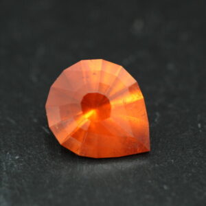 Macro-opname van een 5.3 karaat oranje spessartien granaat in Aqua Drop slijpvorm op zwarte leisteen