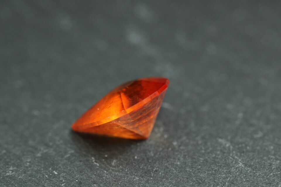 Macro-opname van een 5.3 karaat oranje spessartien granaat in Aqua Drop slijpvorm op zwarte leisteen