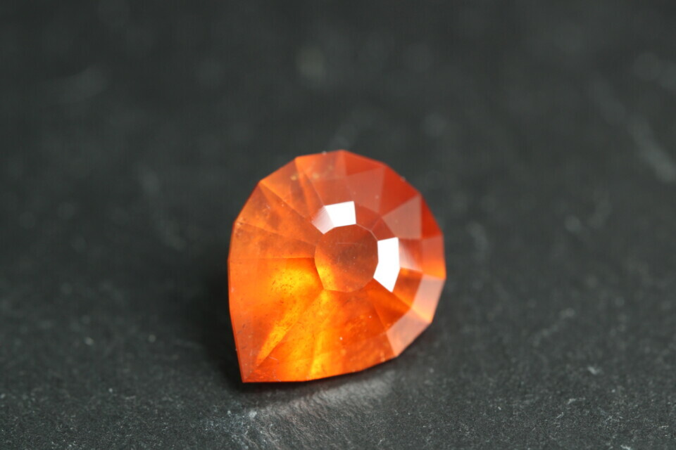 Macro-opname van een 5.3 karaat oranje spessartien granaat in Aqua Drop slijpvorm op zwarte leisteen