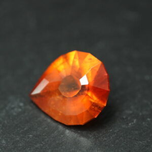 Macro-opname van een 5.3 karaat oranje spessartien granaat in Aqua Drop slijpvorm op zwarte leisteen