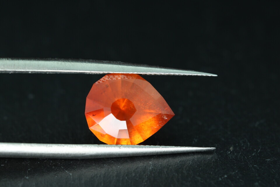 Macro-opname van een 5.3 karaat oranje spessartien granaat in Aqua Drop slijpvorm op zwarte leisteen