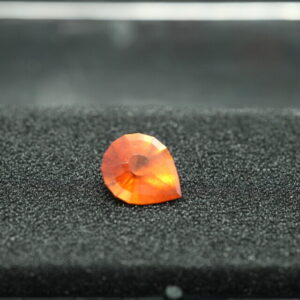 Macro-opname van een 5.3 karaat oranje spessartien granaat in Aqua Drop slijpvorm op zwarte leisteen