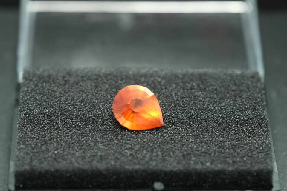 Macro-opname van een 5.3 karaat oranje spessartien granaat in Aqua Drop slijpvorm op zwarte leisteen
